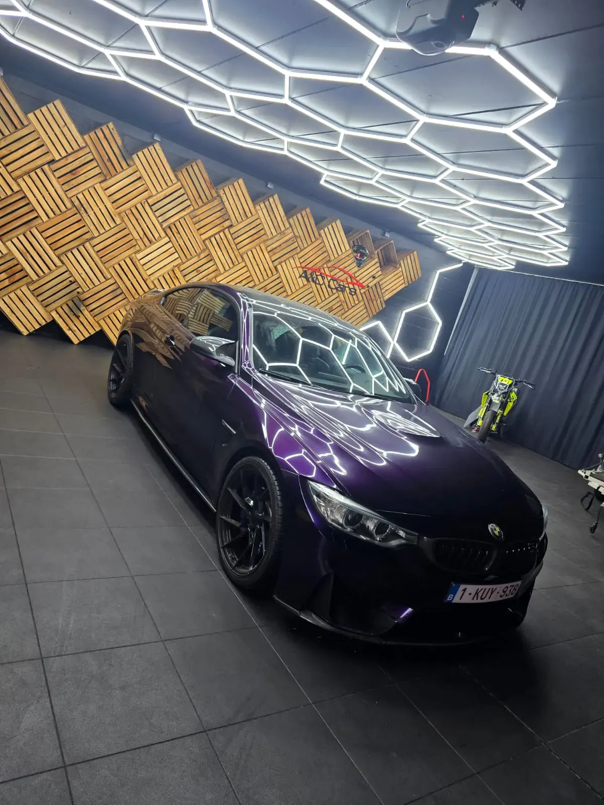 BMW M4 in glanzend paarse wrap onder showroomverlichting